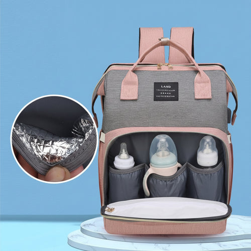 A pink and gray diaper backpack shown open on a light blue background, with three front bottle holders, a diaper pocket, and an inset circle highlighting the insulated lining. Chinese marketing text appears on the image.